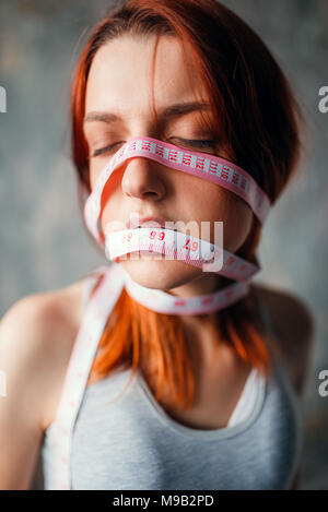 Womans face tied with measuring tape, weight loss Stock Photo