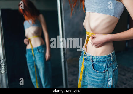 Woman measures waist against mirror, weight loss Stock Photo