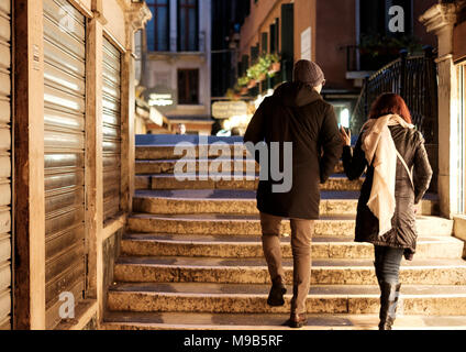 A couple walking after dark in the San Marco area of Venice Stock Photo