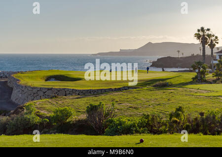 Golf players on a green facing the Atlantic Ocean on the island of Tenerife in Spain Stock Photo