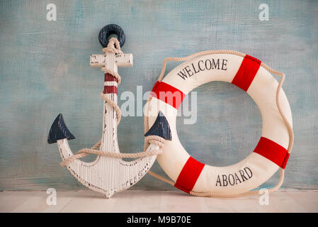 A composition on a sea theme with an anchor and lifebuoy on a blue wall. Stock Photo
