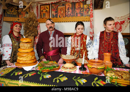 People in Ukrainian native dresses stand behind table set with traditional Easter breads before All-night service.March 23,2018. Kiev,Ukraine Stock Photo