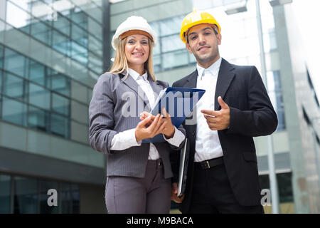 Portrait of smiling architectors who standing with folder near the building. Stock Photo