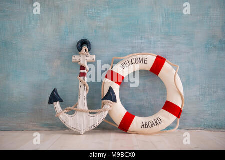 A composition on a sea theme with an anchor and lifebuoy on a blue wall. Stock Photo
