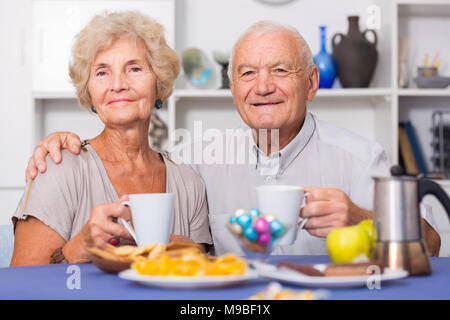 Portrait of happy mature couple having good time drinking tea in kitchen Stock Photo