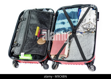 suitcase ready to travel with clothes, book and other elements, on white background Stock Photo