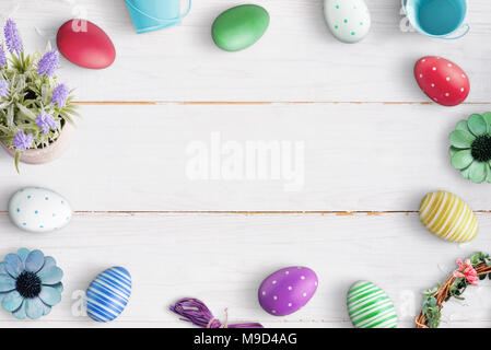 Easter composition with colorful eggs on white wooden background. Free space in the middle for text. Stock Photo
