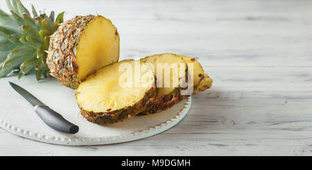 Fresh sliced pineapple on a white wooden cutting board. Top view Stock Photo