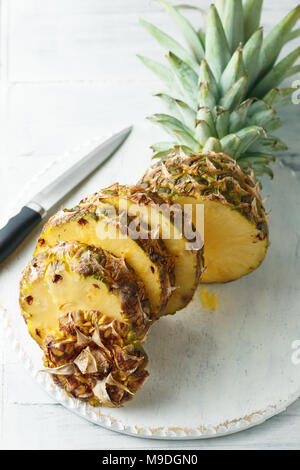 Fresh sliced pineapple on a white wooden cutting board. Top view Stock Photo