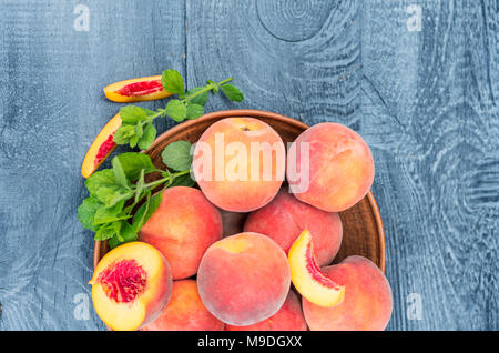 Fresh peaches with mint on wooden background. Top view, flat lay. Closeup. Stock Photo