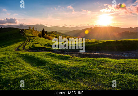 winding road along the grassy rural hill at sunset. gorgeous landscape of Carpathian mountain in springtime Stock Photo