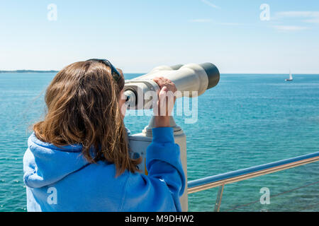 Woman looking through coin operated binoculars at seaside. Stock Photo