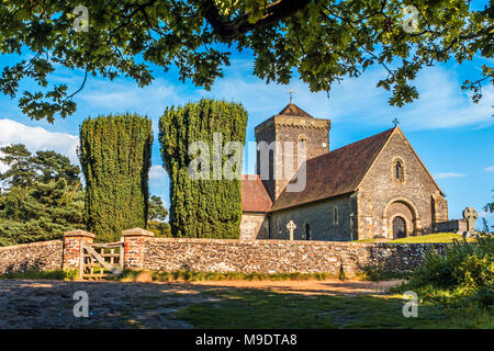 Church of St Martha-on-the-Hill in the North Downs of Surrey, Guildford, on beautiful sunny day with pruned trees, walled graveyard and gate Stock Photo