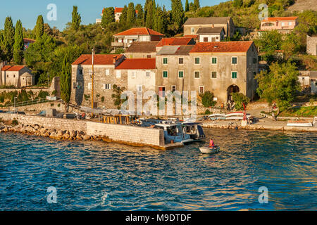 A man sets of in motorboat, from Adriatic sea island of Osljak with old mediterranean houses on the shore, in the Zadar archipelago, Dalmatia, Croatia Stock Photo