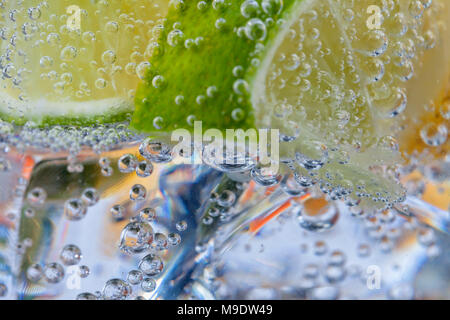 Homemade cocktail with citrus fruits in glass cup with transparent drink ices and bubbles. Stock Photo