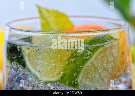 Homemade cocktail with citrus fruits in glass cup with transparent drink ices and bubbles. Stock Photo