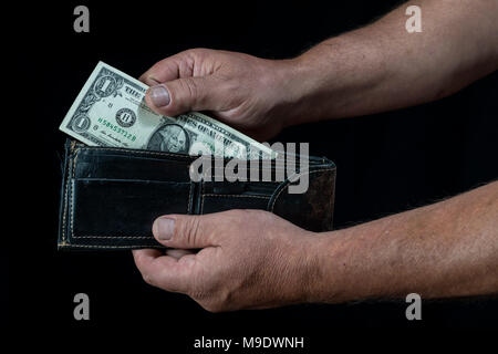 hands of man taking a one dollar bill from a wallet, on a black background Stock Photo