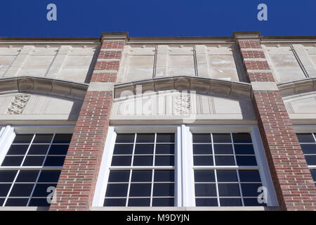 Upward view of a stately century-old school building with unique white stone and red brick accent and large white windows Stock Photo