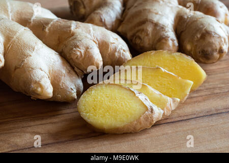 Whole and sliced ginger root on a wooden table Stock Photo