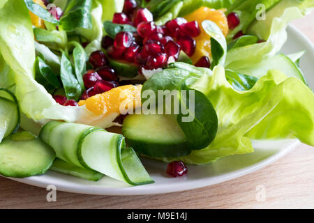 Vegetable salad with lettuce, corn salad, cucumber, avocado, orange, and pomegranate seeds. Stock Photo