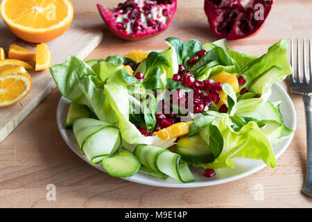 Vegetable salad with lettuce, corn salad, cucumber, avocado, orange, and pomegranate seeds. Stock Photo