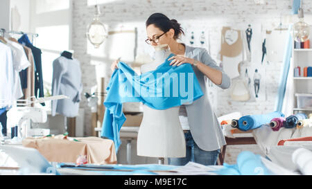 Beautiful Female fashion, designer,  Adjusting Fabrics on a Tailored Mannequin. In Her Studio Various Sewing Items and Colorful Fabrics Laying around Stock Photo