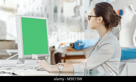 Beautiful fashion, designer,  Sits at Her Desk before Personal Computer with Green Screen, Using Digital Drawing Tablet. Her Studio is Sunny Stock Photo