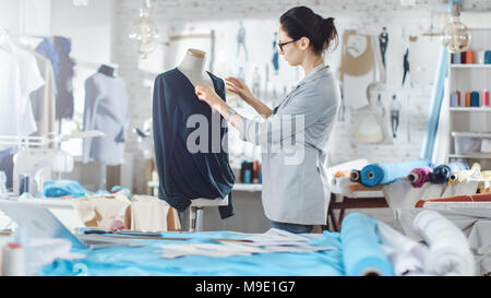 Beautiful Woman fashion, designer,  Working with Tailoring Mannequin, Adjusting Blouse. Her Studio is Bright and Sunny, Mannequins Standing around Stock Photo