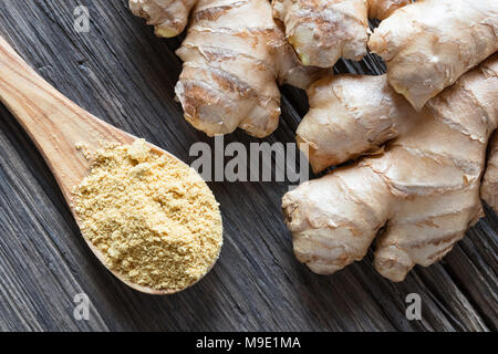 Ground ginger and fresh ginger root on a wooden background, top view Stock Photo