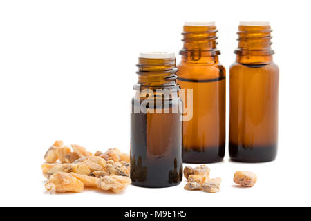A bottle of styrax benzoin essential oil with styrax benzoin resin and other bottles on a white background