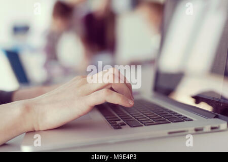 close up of business womans hand typing on laptop  at modern startup office computer, blured team in meeting, people group in background Stock Photo