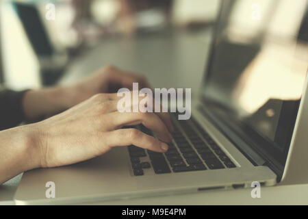 close up of business womans hand typing on laptop  at modern startup office computer, blured team in meeting, people group in background Stock Photo