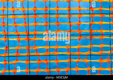 Dark wire grid and plastic protective mesh of an orange color against smooth bluish background Stock Photo