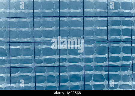 Dark wire grid and plastic protective mesh of an light blue color against smooth blue background Stock Photo