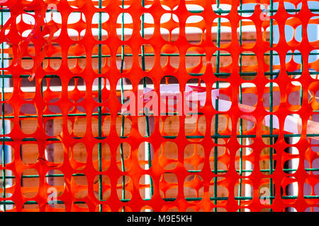 Several layers of an orange protective mesh, green metal wire grid and warning tape. Closeup view Stock Photo