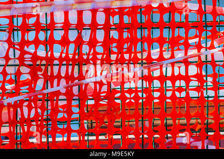 Several layers of an orange protective mesh, green metal wire grid and warning tape. Closeup view Stock Photo