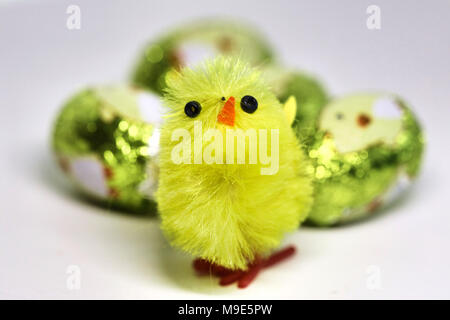 A small yellow chick is set against a cluster of mini chocolate easter eggs Stock Photo