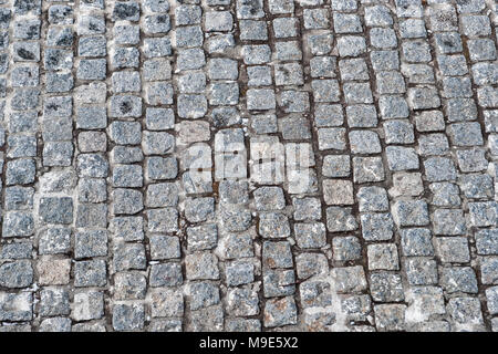 Surface paved with rows of grey granite stone blocks of irregular shapes Stock Photo