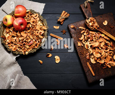 Dried pieces of apples in an iron plate and on a brown wooden board, top view, empty space in the middle Stock Photo