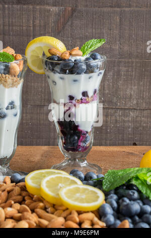 Healthy Treat - greek yogurt in a fancy dessert glass - parfait with fresh blueberries, chopped almonds, granola, a squeeze of lemon and mint sprig Stock Photo