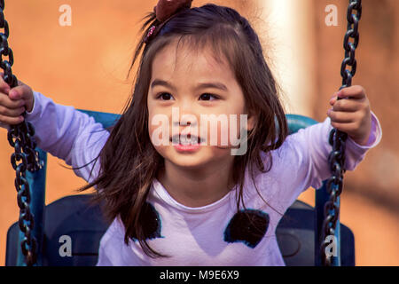 Cute little mixed race girl on a swing Stock Photo