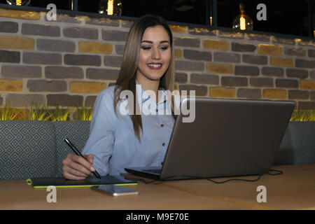 Graphic designer sitting at table in cafe and  using digital tablet and computer tools working on a new project. Stock Photo