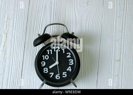 Black retro alarm clock on wood table, time concept idea. Stock Photo