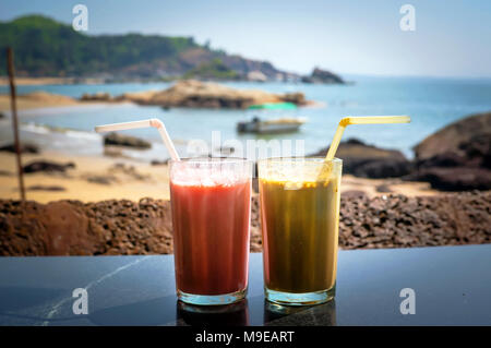 Two glasses with cocktails in glasses on the background of sea and sky. Coffee cocktail and a strawberry smoothie for Breakfast. Stock Photo