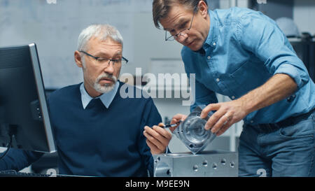 Two Senior Engineers Discuss Important Technical Components, Joining Them Together. Both are Experienced and Wise. Their Office Looks Modern Stock Photo