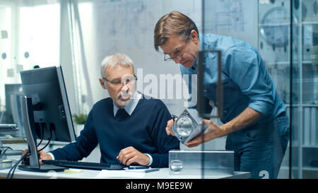 Two Senior Engineers Discuss Important Technical Component. Both are Experienced and Wise. Their Office Looks Modern and Bright. Stock Photo