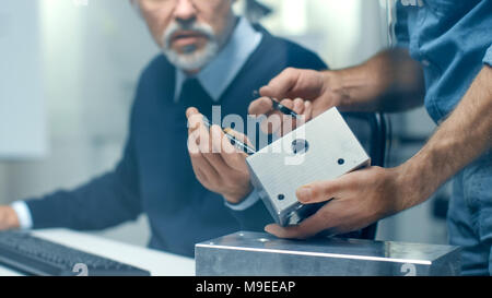 Close-up Shot of a Two Senior Engineers Discuss Important Technical Components, Joining Them Together. Both are Experienced and Wise. Stock Photo