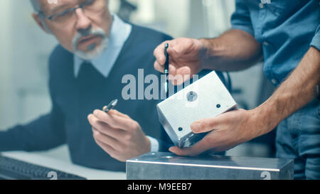 Close-up Shot of a Two Senior Engineers Discuss Important Technical Components, Joining Them Together. Both are Experienced and Wise. Stock Photo