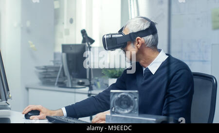 Virtual Reality Engineer Works with VR Glasses On while Simultaneously Doing Programming on His Personal Computer. Stock Photo
