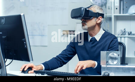 Virtual Reality Engineer Works with VR Glasses On while Simultaneously Doing Programming on His Personal Computer. Stock Photo